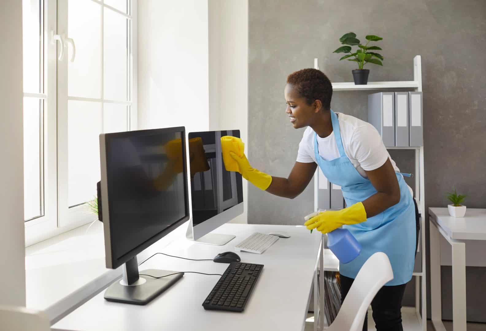 Woman cleaning office computer screens